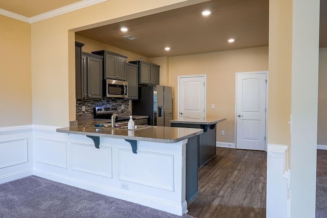 kitchen featuring visible vents, stainless steel microwave, a kitchen breakfast bar, refrigerator with ice dispenser, and a sink