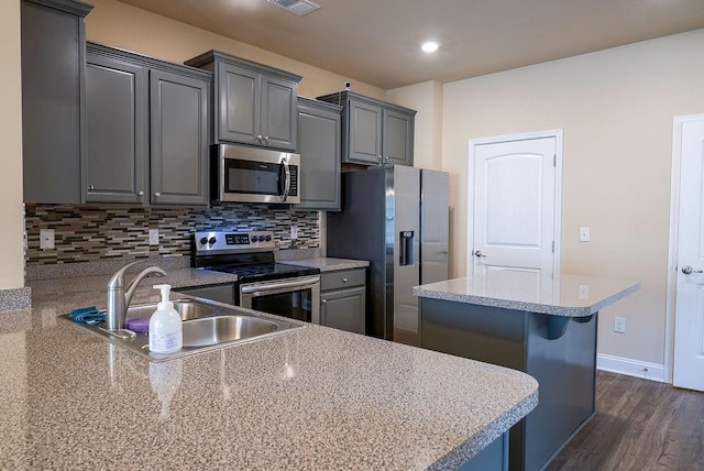 kitchen with stainless steel appliances, tasteful backsplash, gray cabinets, and a sink