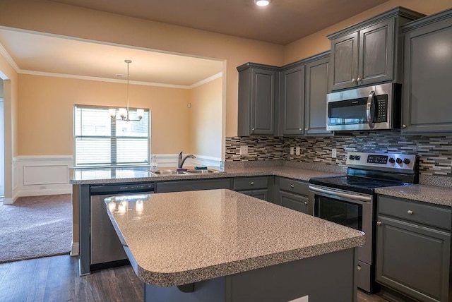 kitchen featuring stainless steel appliances, gray cabinetry, ornamental molding, wainscoting, and a sink