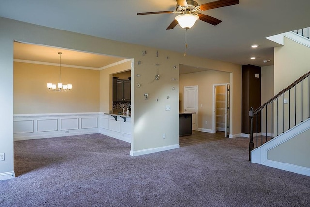 empty room with ceiling fan with notable chandelier, ornamental molding, stairway, and carpet flooring