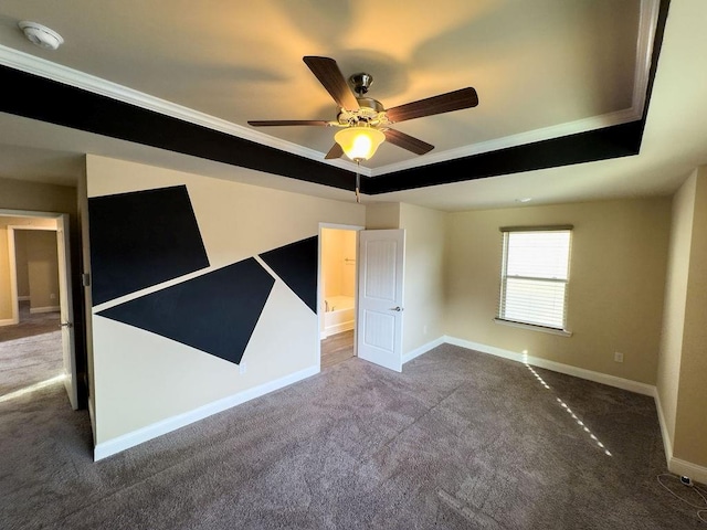 empty room with carpet floors, a tray ceiling, a ceiling fan, and baseboards