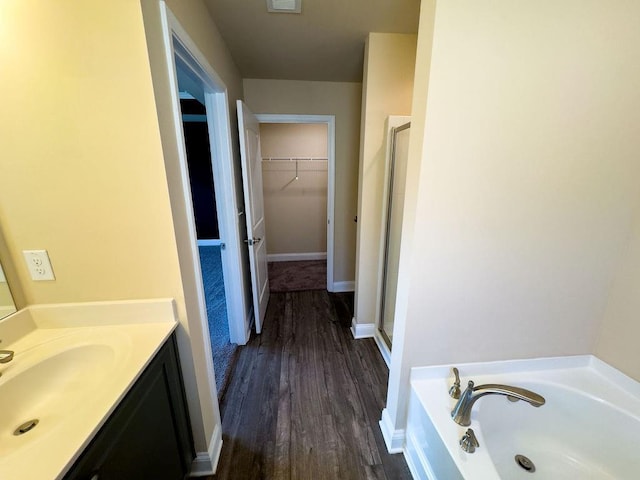 full bath featuring a stall shower, a walk in closet, vanity, and a bath