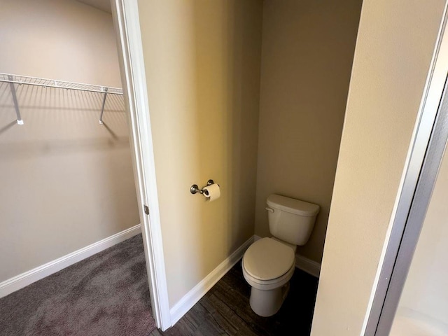 bathroom featuring toilet, a spacious closet, and baseboards