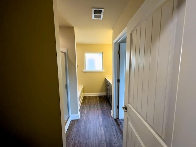 hallway with dark wood-style floors, visible vents, and baseboards