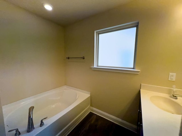 bathroom with recessed lighting, baseboards, a bath, and vanity