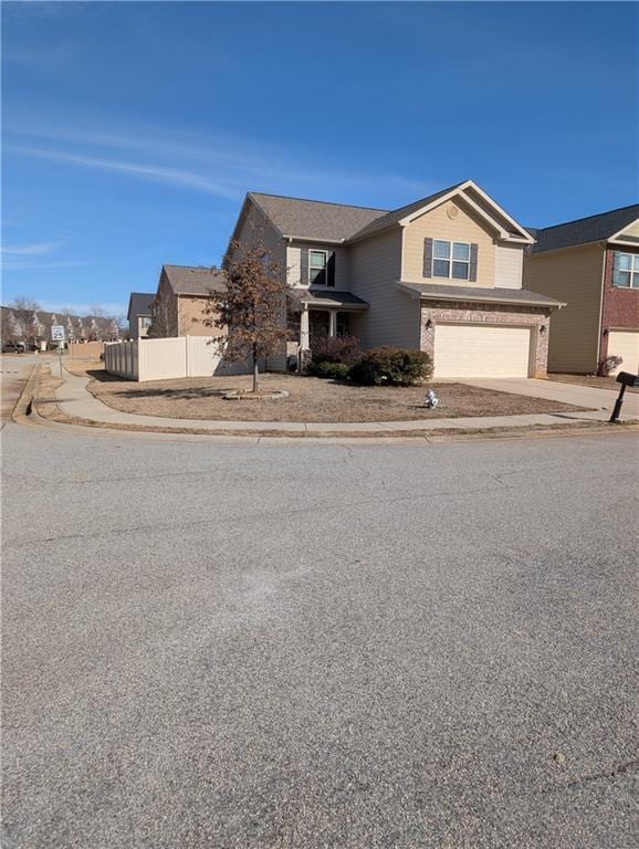 traditional-style house featuring concrete driveway, brick siding, an attached garage, and fence