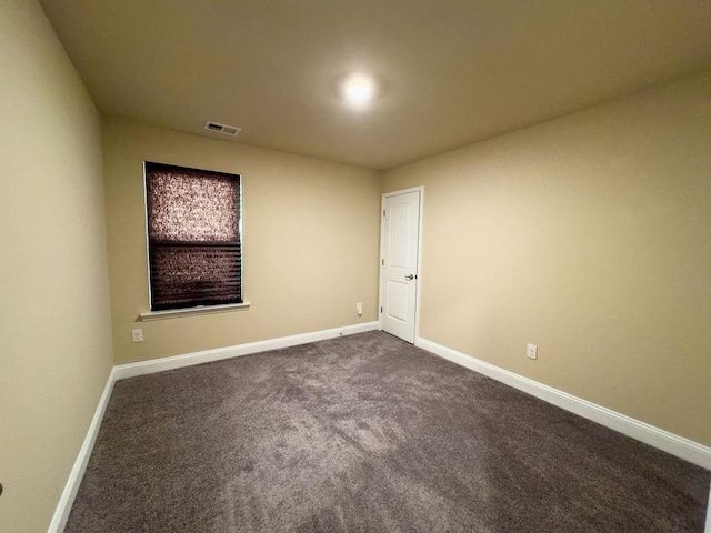 spare room featuring baseboards, visible vents, and dark colored carpet