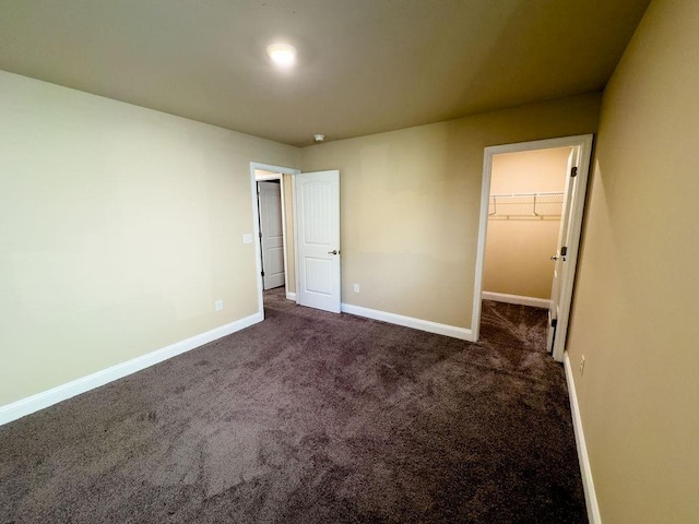 unfurnished bedroom featuring a spacious closet, a closet, carpet, and baseboards