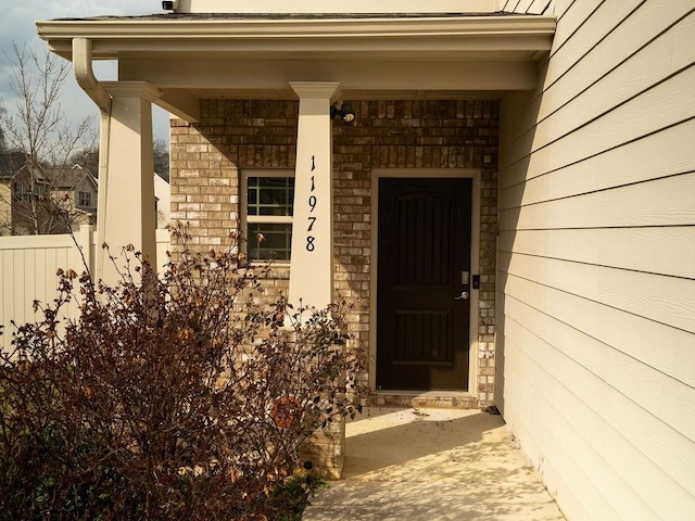 property entrance featuring brick siding and fence