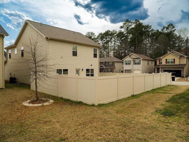 back of house featuring a yard, central AC, and fence