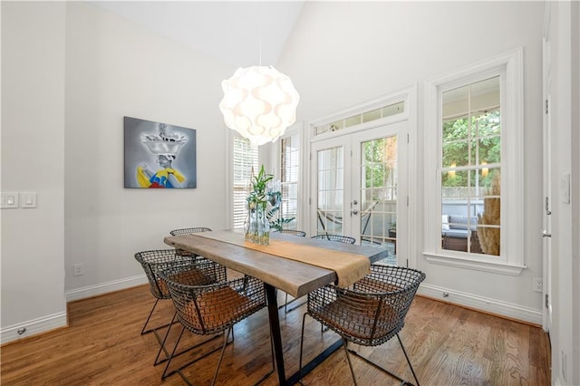 dining area featuring baseboards, wood finished floors, a chandelier, and french doors