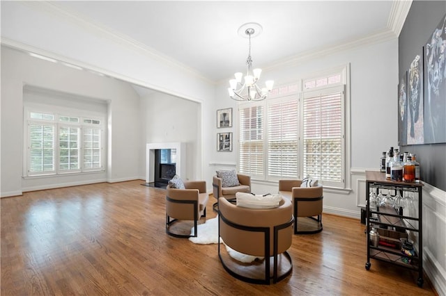living room with a chandelier, wood finished floors, a high end fireplace, crown molding, and baseboards