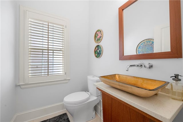 bathroom featuring toilet, vanity, and baseboards