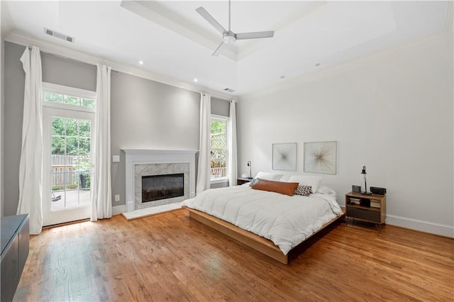 bedroom featuring multiple windows, access to outside, crown molding, wood finished floors, and a high end fireplace