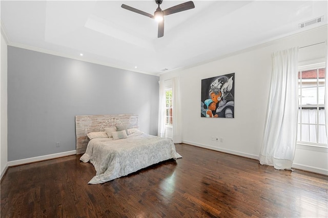 bedroom with a tray ceiling, wood finished floors, crown molding, baseboards, and ceiling fan