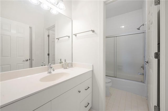 full bathroom featuring toilet, vanity, tile patterned flooring, and combined bath / shower with glass door
