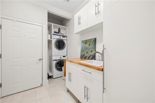 laundry room featuring stacked washer and clothes dryer, crown molding, and light tile patterned floors