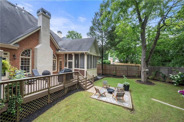 view of yard featuring a deck, a sunroom, an outdoor fire pit, and a patio area