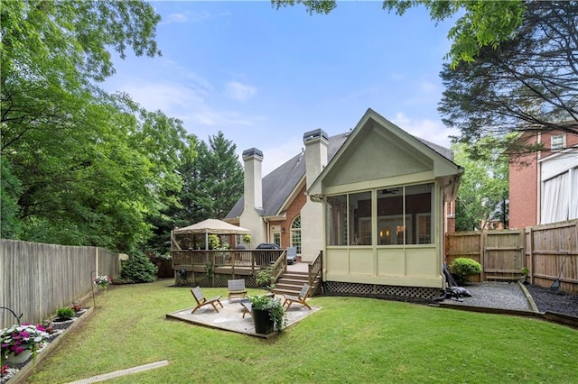back of property featuring a wooden deck, a sunroom, a chimney, and a patio area