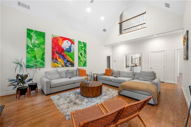 living area featuring high vaulted ceiling, baseboards, and wood finished floors