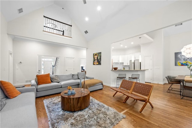 living area with high vaulted ceiling, light wood-type flooring, recessed lighting, and baseboards
