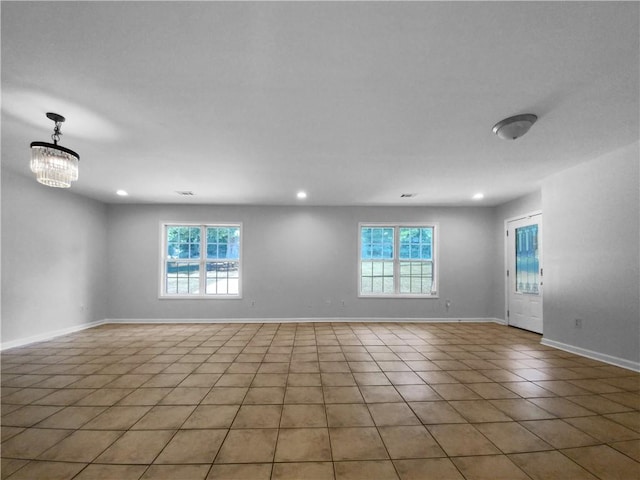 tiled empty room featuring a chandelier