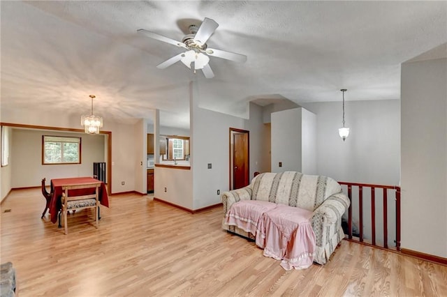 living room with ceiling fan with notable chandelier, a wealth of natural light, and light wood-type flooring