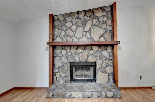 interior details with wood-type flooring and a stone fireplace