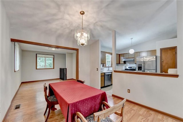 dining area with lofted ceiling, sink, light hardwood / wood-style flooring, and a chandelier