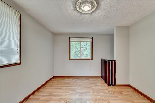 empty room with a textured ceiling and light hardwood / wood-style flooring