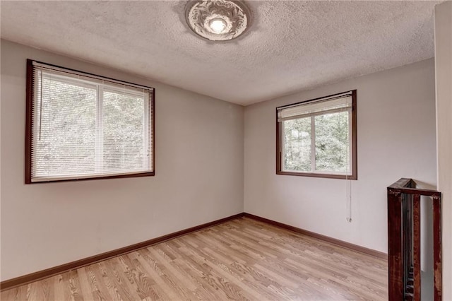 empty room featuring light wood-type flooring and a textured ceiling