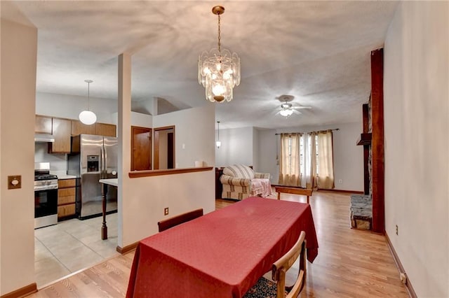 dining room featuring vaulted ceiling, ceiling fan with notable chandelier, and light hardwood / wood-style floors