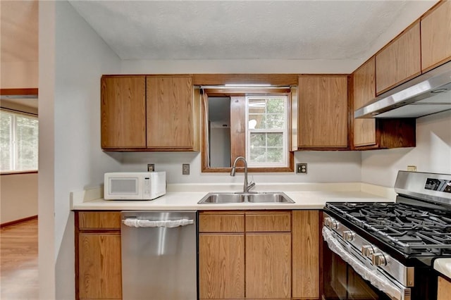 kitchen featuring wood-type flooring, appliances with stainless steel finishes, sink, and extractor fan