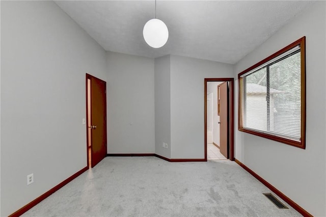 empty room with vaulted ceiling and light colored carpet