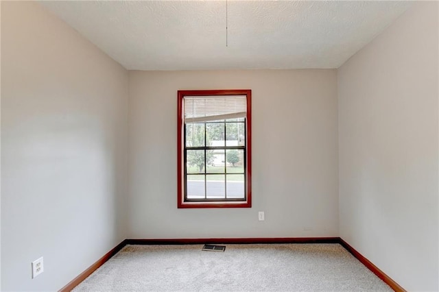 carpeted empty room featuring a textured ceiling