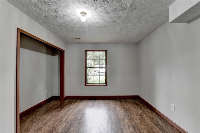 unfurnished bedroom featuring a closet, a textured ceiling, and dark wood-type flooring