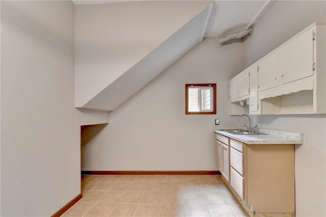 kitchen featuring vaulted ceiling, light tile patterned floors, and sink