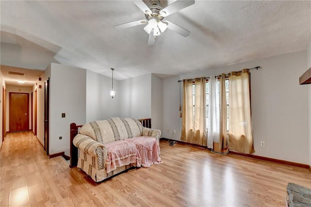 living room with light hardwood / wood-style floors, ceiling fan, and a textured ceiling