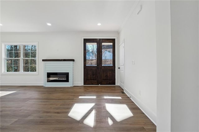 foyer entrance featuring crown molding, plenty of natural light, and dark hardwood / wood-style flooring