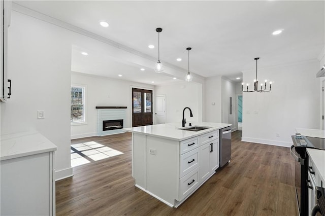 kitchen with sink, appliances with stainless steel finishes, an island with sink, white cabinets, and decorative light fixtures