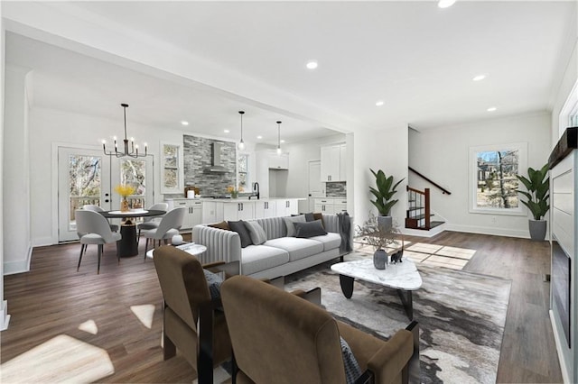 living room featuring dark hardwood / wood-style flooring, sink, a notable chandelier, and ornamental molding