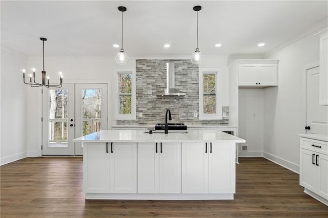 kitchen featuring a kitchen island with sink, hanging light fixtures, and wall chimney range hood