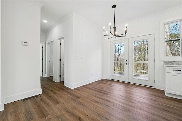 unfurnished dining area with dark hardwood / wood-style flooring, crown molding, french doors, and an inviting chandelier