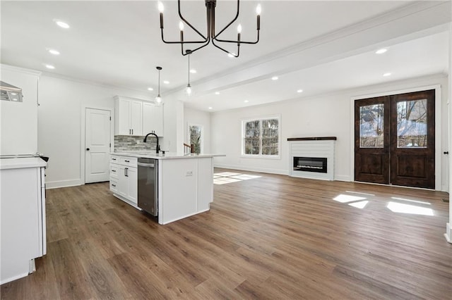 kitchen with decorative light fixtures, white cabinetry, dishwasher, backsplash, and a center island with sink