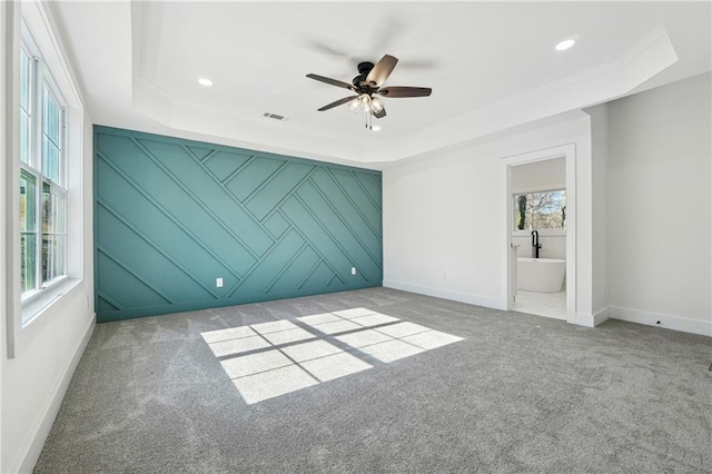 spare room featuring ceiling fan, light colored carpet, and a tray ceiling