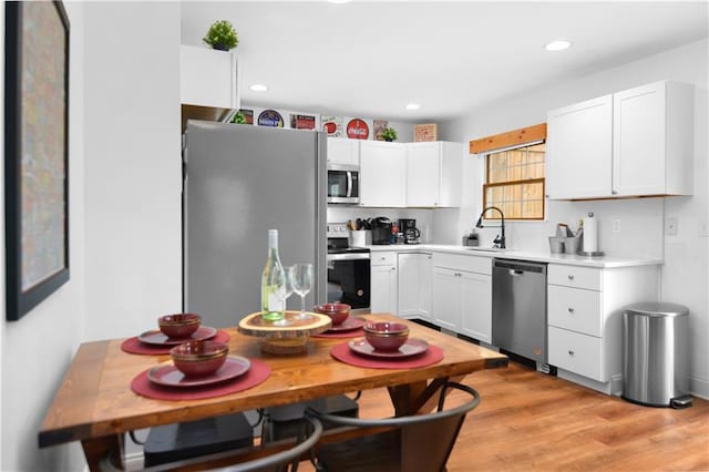 kitchen with white cabinetry, stainless steel appliances, sink, and light hardwood / wood-style floors