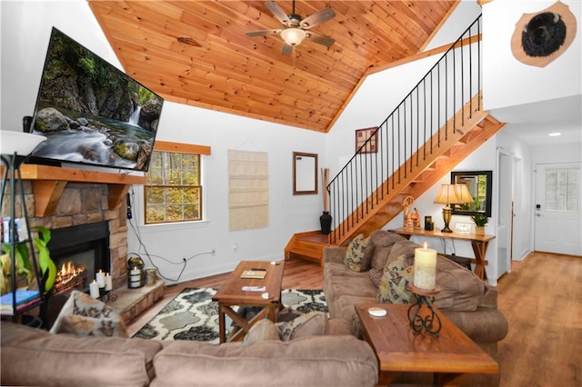 living room featuring ceiling fan, wood-type flooring, a fireplace, and wood ceiling