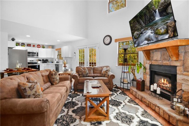 living room featuring a stone fireplace, french doors, sink, and hardwood / wood-style flooring