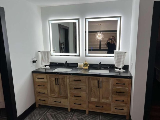 bathroom featuring an inviting chandelier, double vanity, and a sink