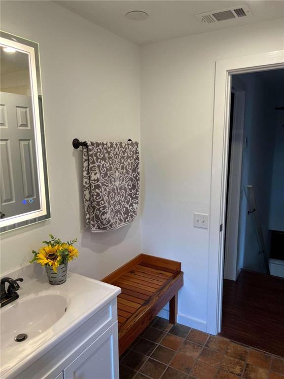 bathroom with visible vents, vanity, and stone finish flooring